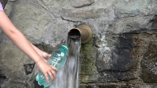 Imagen de una persona llenando una botella de agua
