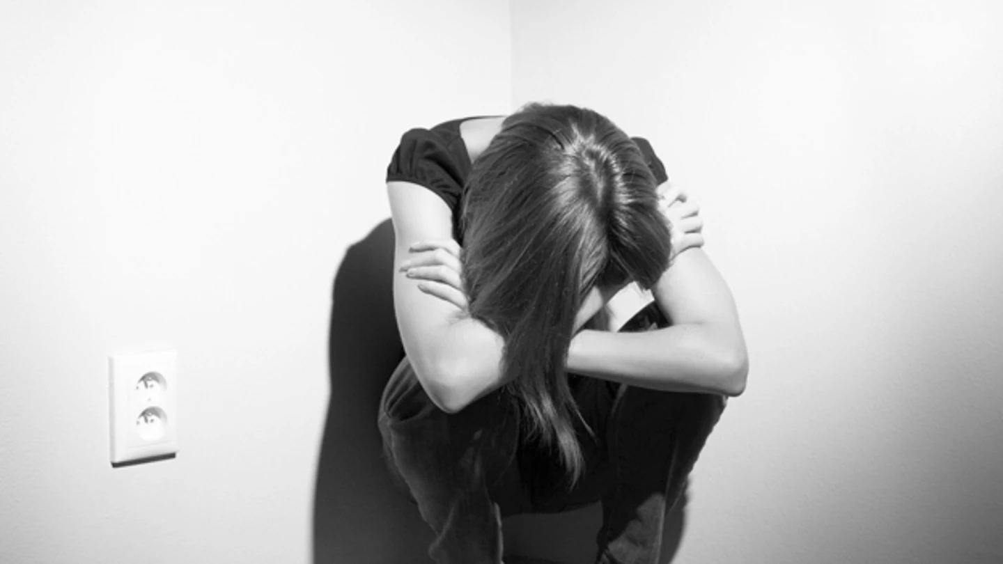 Una mujer, en cuclillas en un rincón Una mujer, en cuclillas en un rincón
