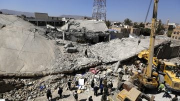 Un grupo de personas inspeccion los restos de la sede principal de la Policía tras un bombardeo en Yemen