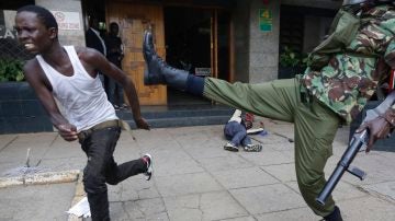 Un hombre corre para evitar ser golpeado por un agente de policía
