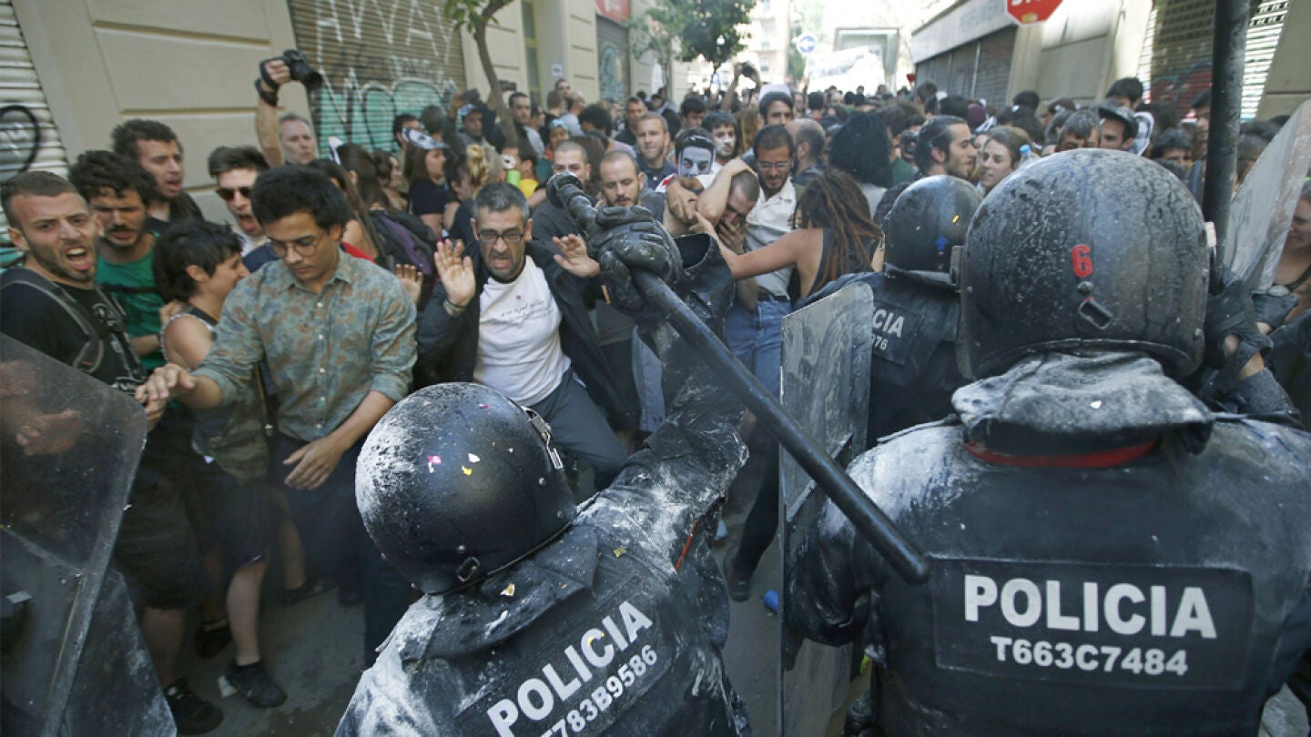 Manifestantes y antidisturbios de los Mossos d'Esquadra, durante los incidentes producidos en el barrio de Gr&agrave;cia