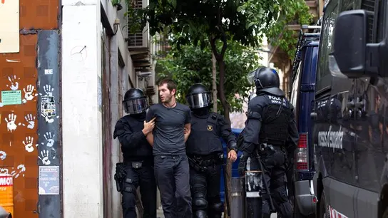 Los Mossos d'Esquadra custodian a uno de los okupas detenidos Los Mossos d'Esquadra custodian a uno de los okupas detenidos