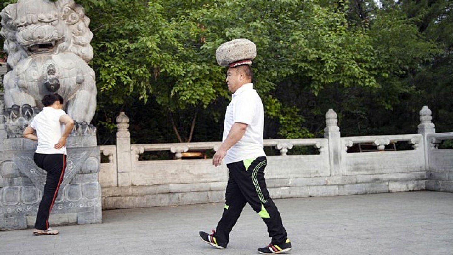 Cong Yan caminando con una piedra en la cabeza