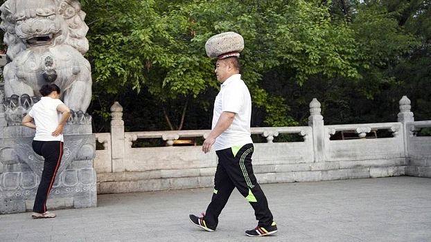 Cong Yan caminando con una piedra en la cabeza