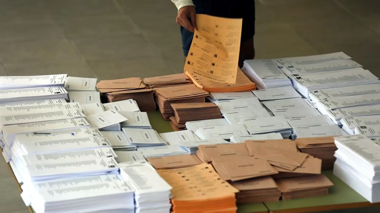 Un votante selecciona las papeletas antes de votar Un votante selecciona las papeletas antes de votar