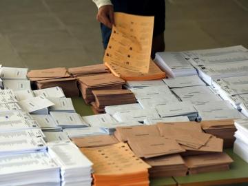Un votante selecciona las papeletas antes de votar Un votante selecciona las papeletas antes de votar