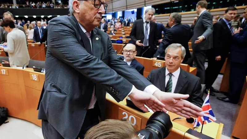 Juncker, intenta tapar la cámara a un fotógrafo que enfoca a Farage