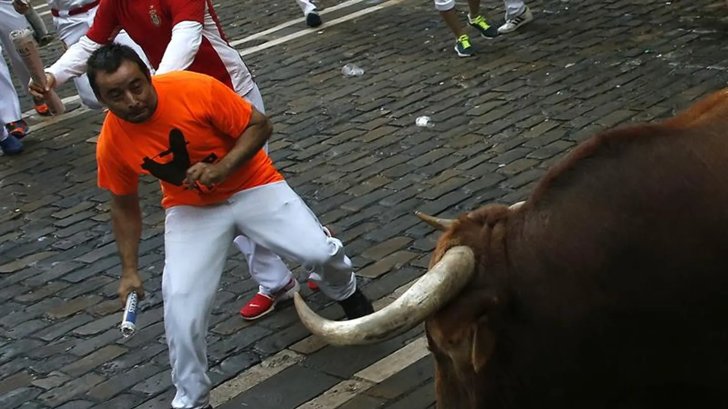 Un mozo esquiva a un toro durante un encierro en San Fermín Un mozo esquiva a un toro durante un encierro en San Fermín