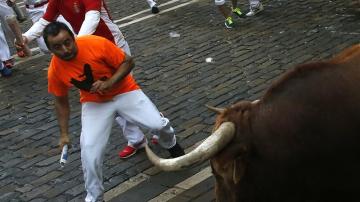 Un mozo esquiva a un toro durante un encierro en San Fermín
