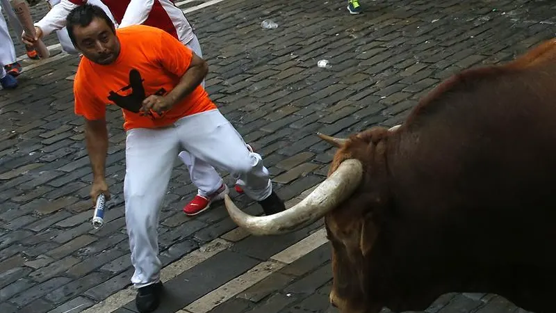 Un mozo esquiva a un toro durante un encierro en San Fermín