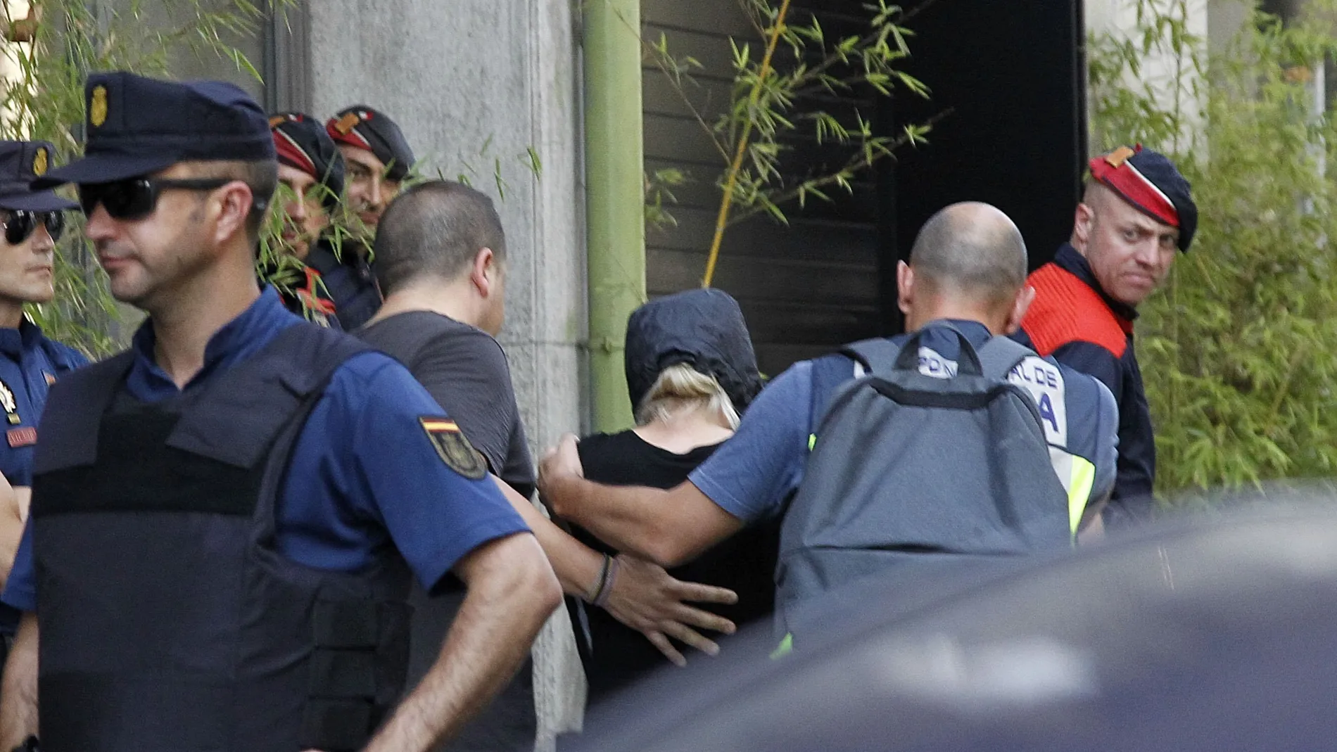 Mossos d'Esquadra y Policía Nacional custodian a uno de los detenidos