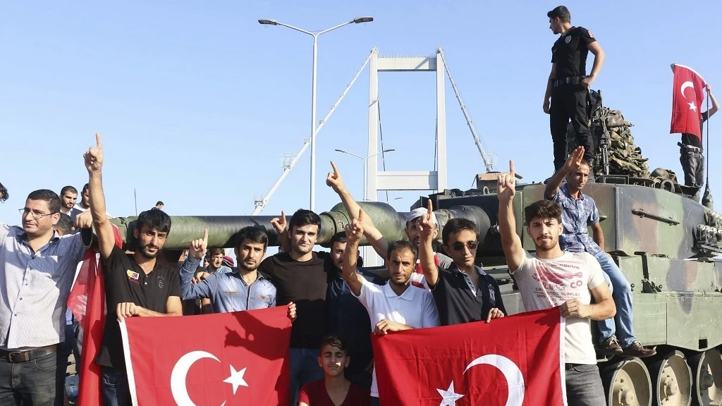 Partidarios del presidente Recep Tayyip Erdogan muestran la bandera nacional junto a un tanque.