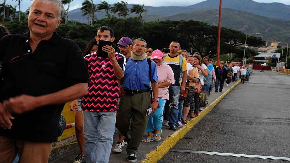 Un grupo de personas forma una fila en el puente fronterizo "Simón Bolívar" entre Colombia y Venezuela.