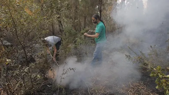 Dos vecinos intentan sofocar un foco del incendio que afecta al municipio coruñés de Porto Do San Dos vecinos intentan sofocar un foco del incendio que afecta al municipio coruñés de Porto Do San