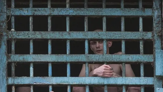Dos prisioneros miran a través de los barrotes de su celda en la prisión Dos prisioneros miran a través de los barrotes de su celda en la prisión