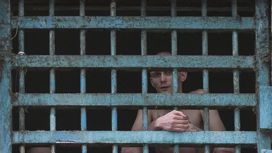 Dos prisioneros miran a través de los barrotes de su celda en la prisión Dos prisioneros miran a través de los barrotes de su celda en la prisión