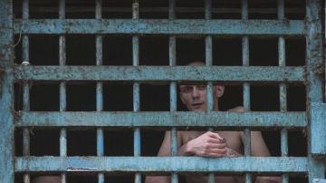 Dos prisioneros miran a través de los barrotes de su celda en la prisión