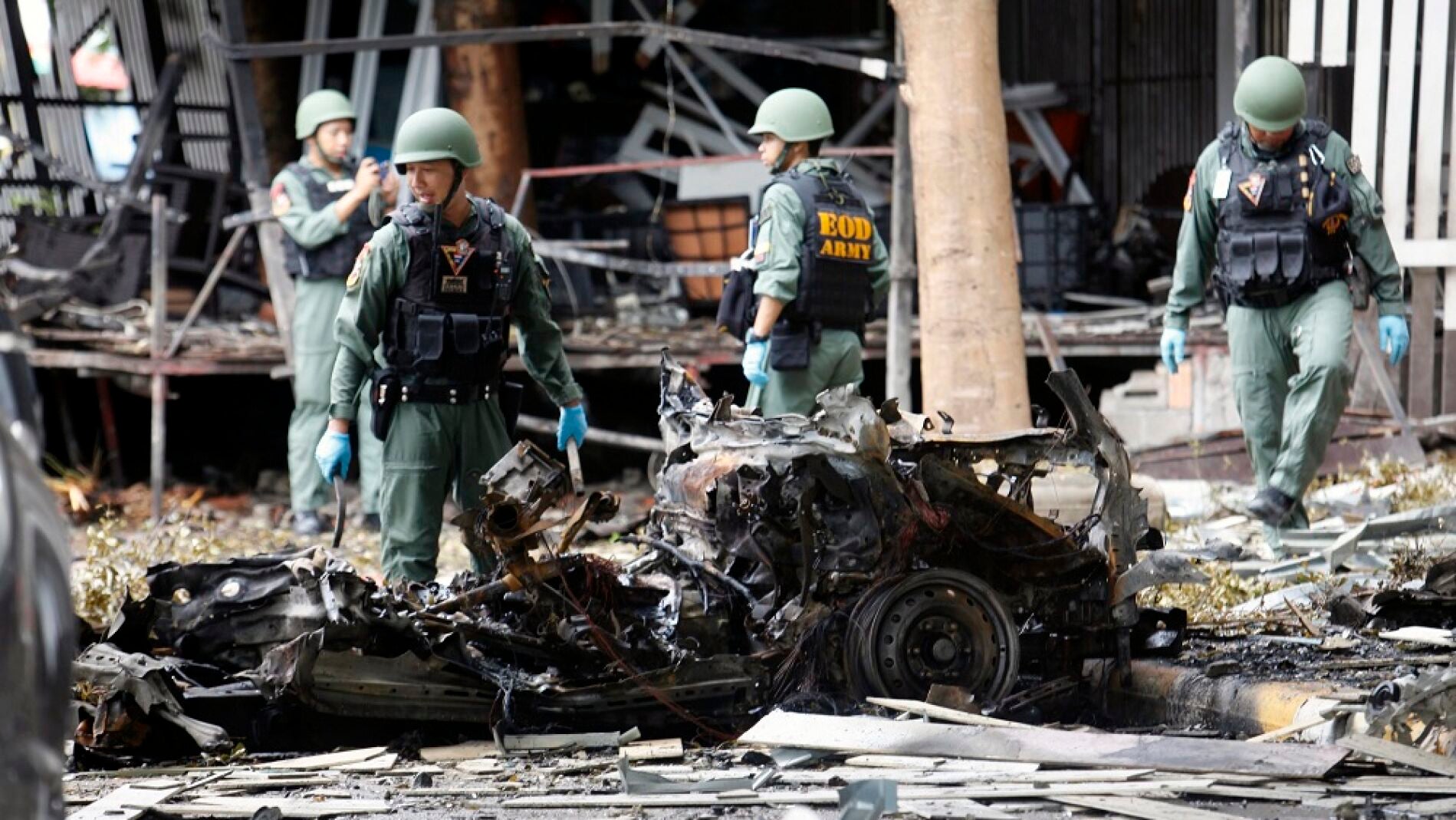 Integrantes del escuadrón antiexplosivos de tailandés EOD inspeccionan los restos de un vehículo