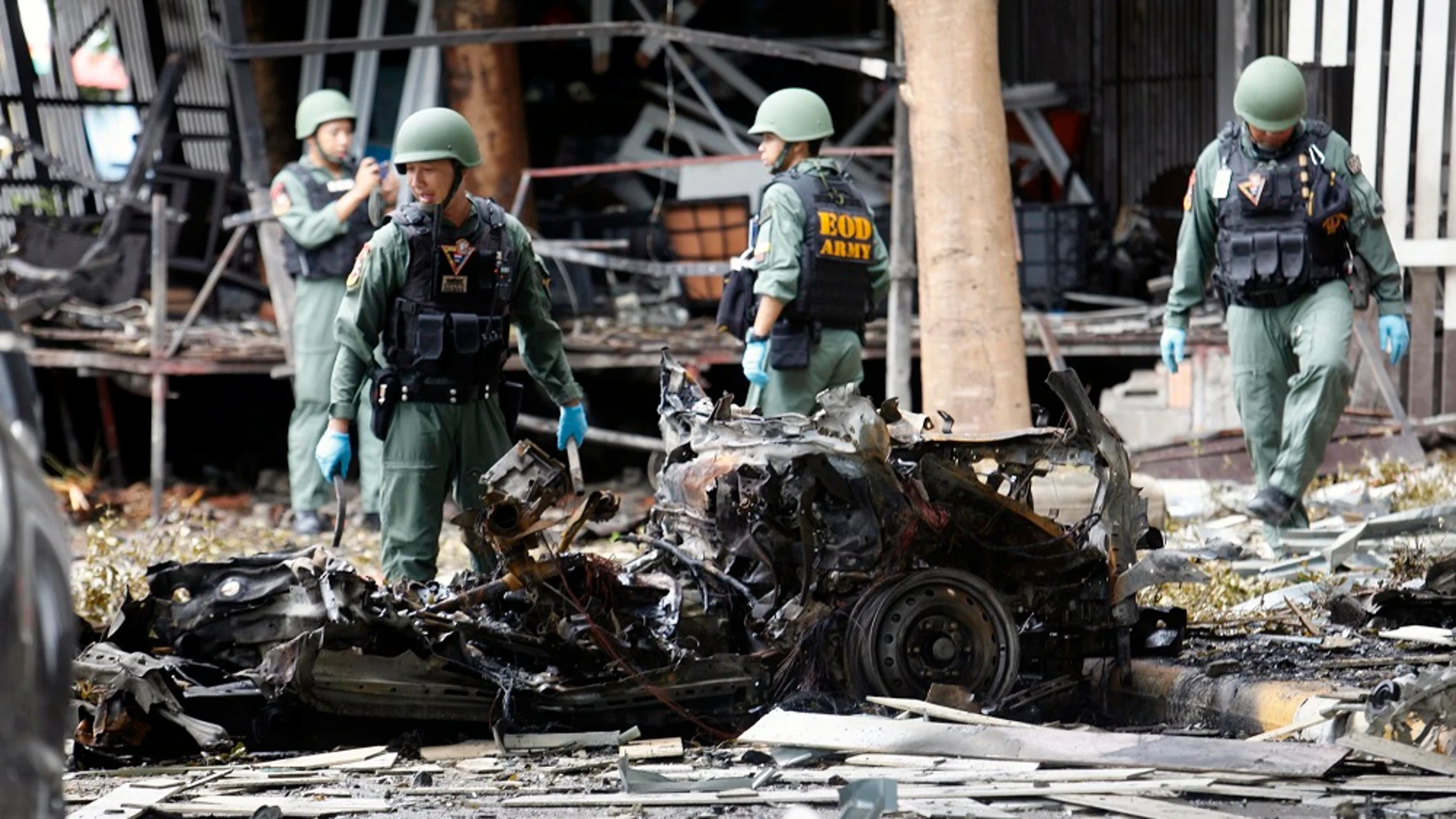 Integrantes del escuadrón antiexplosivos de tailandés EOD inspeccionan los restos de un vehículo Integrantes del escuadrón antiexplosivos de tailandés EOD inspeccionan los restos de un vehículo