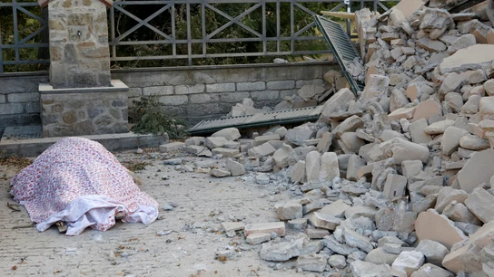 Un cuerpo cubierto con una manta junto a los escombros Un cuerpo cubierto con una manta junto a los escombros