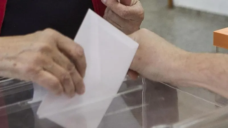 Una persona deposita su voto en unas elecciones Una persona deposita su voto en unas elecciones