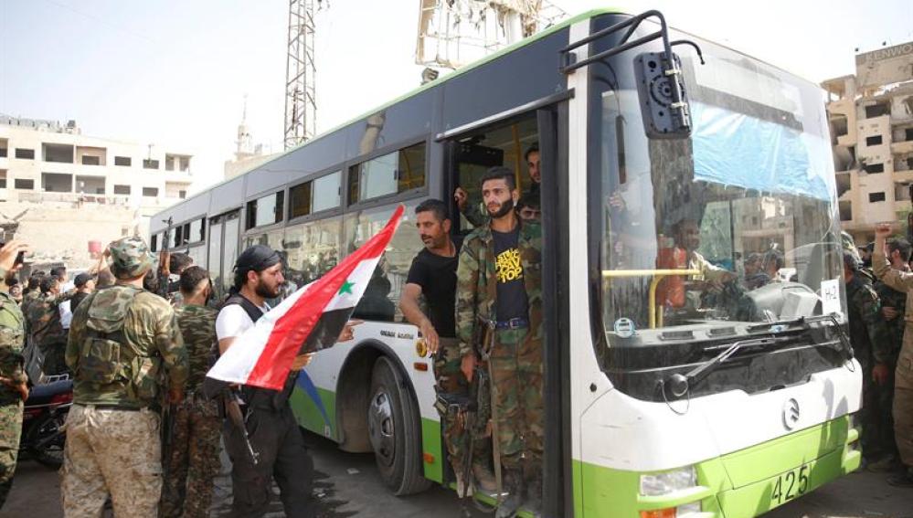 Civiles y combatientes de la población rebelde de Daraya abandonan la ciudad con autobuses proporcionados por el gobierno, en Siria