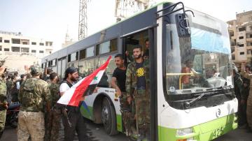 Civiles y combatientes de la población rebelde de Daraya abandonan la ciudad con autobuses proporcionados por el gobierno, en Siria