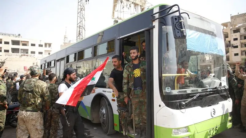 Civiles y combatientes de la poblaci&oacute;n rebelde de Daraya abandonan la ciudad con autobuses proporcionados por el gobierno, en Siria,