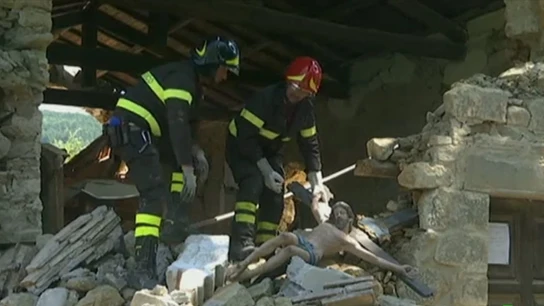 Dos bomberos sujetan una imagen de un cristo en Italia Dos bomberos sujetan una imagen de un cristo en Italia