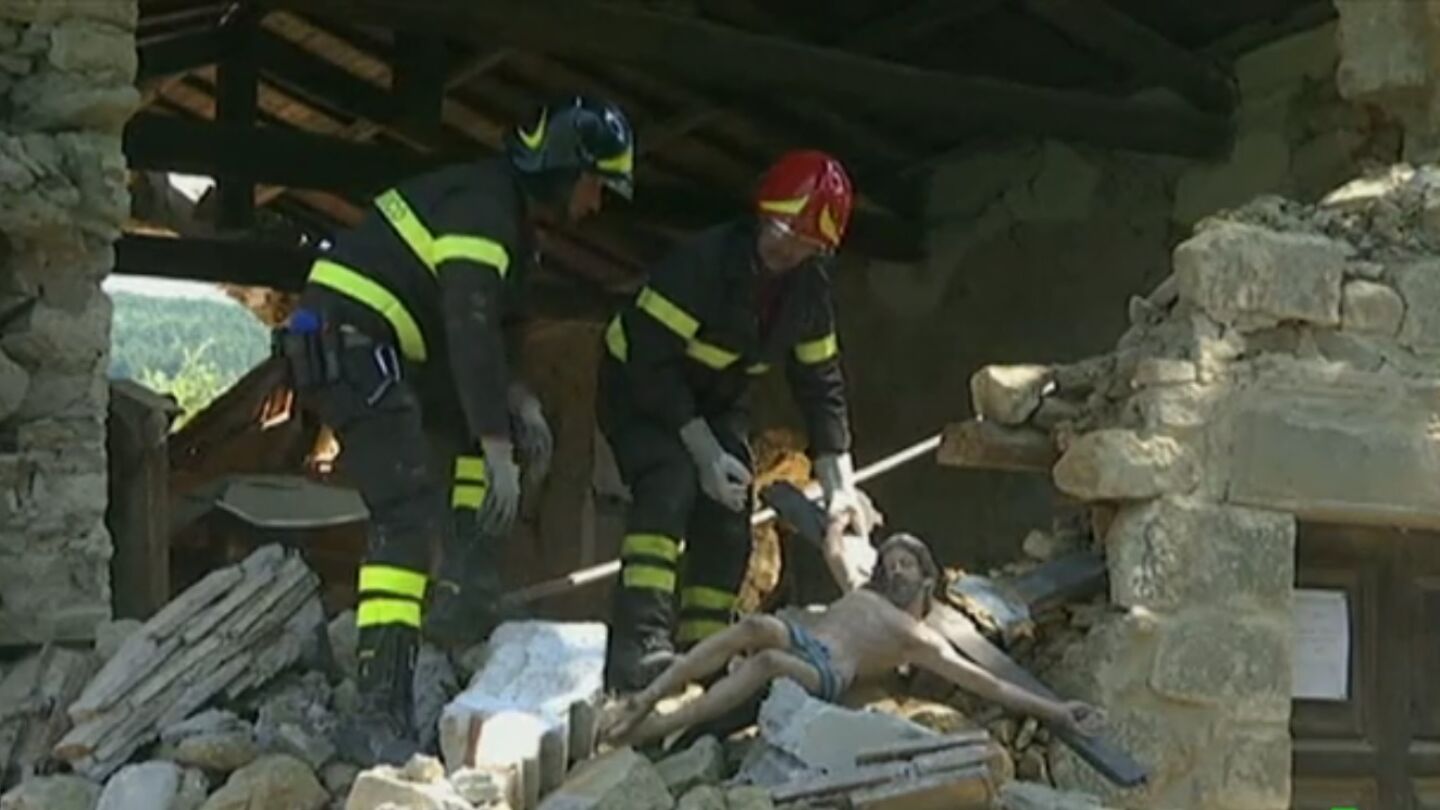 Dos bomberos sujetan una imagen de un cristo en Italia