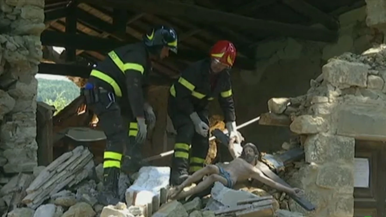 Dos bomberos sujetan una imagen de un cristo en Italia