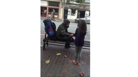 Una ni&ntilde;a comparte su comida con un vagabundo.