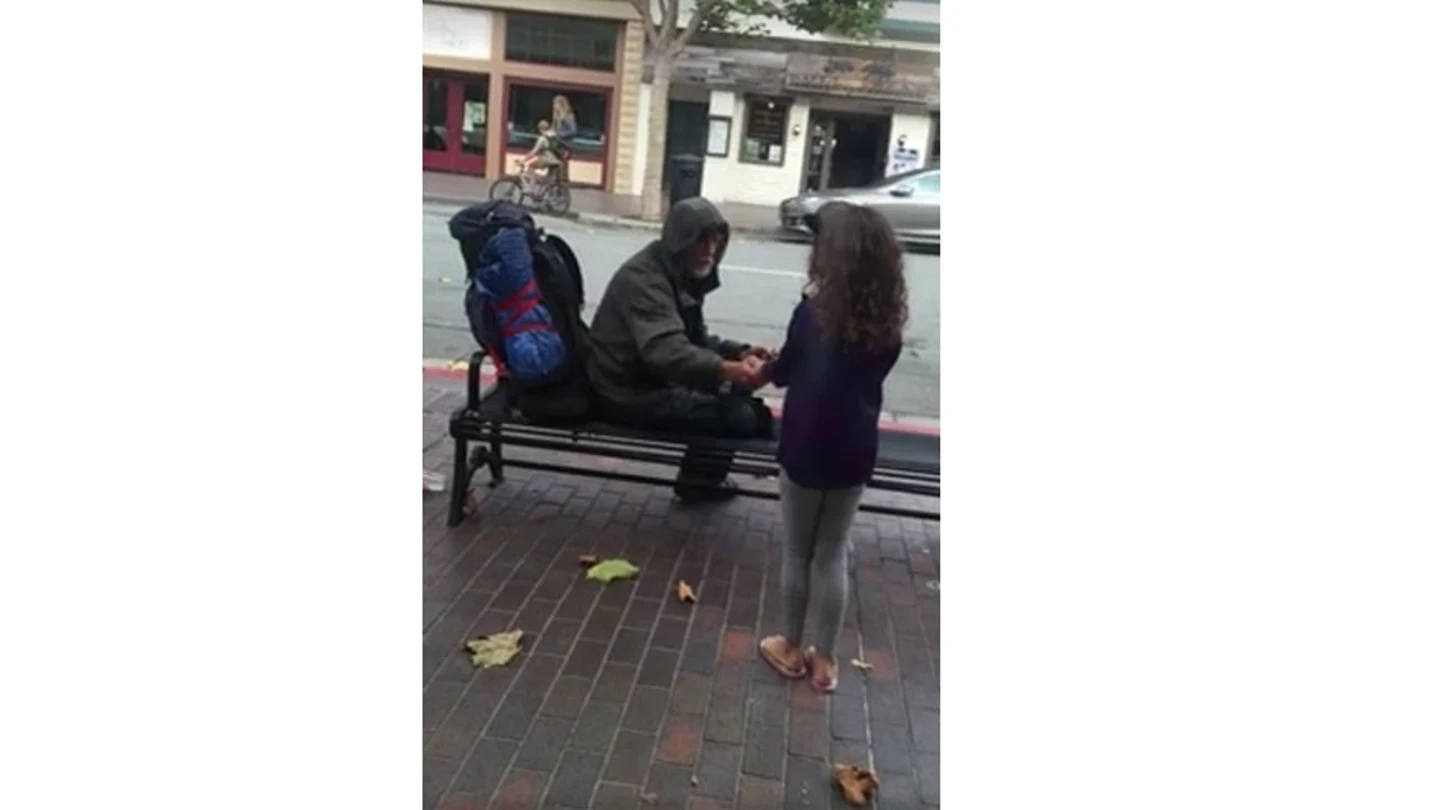 Una niña comparte su comida con un vagabundo. Una niña comparte su comida con un vagabundo.