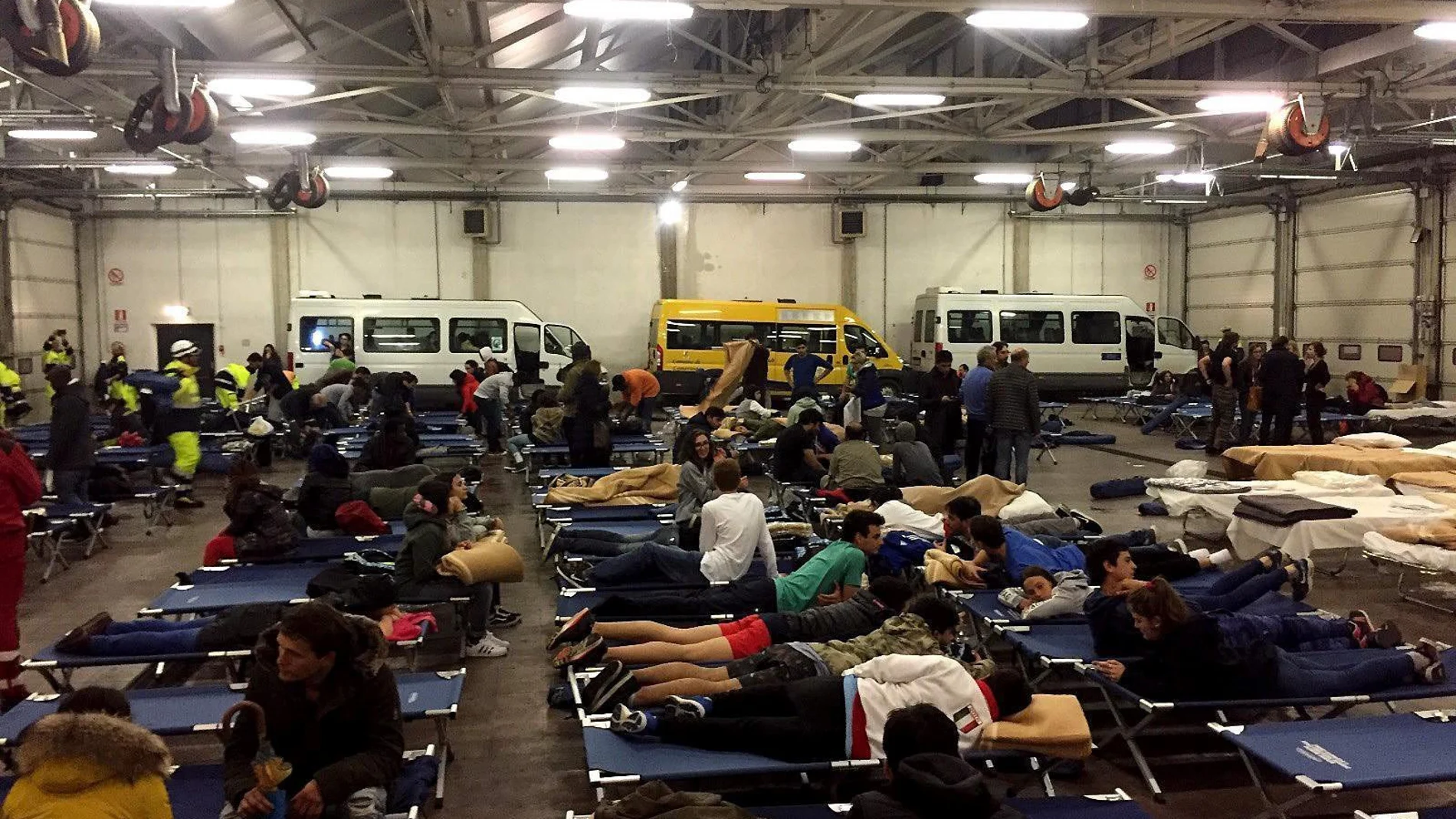 Personas evacuadas por los terremotos, pasan la noche en un hangar de autobuses convertido en refugio temporal, en Camerino, Italia