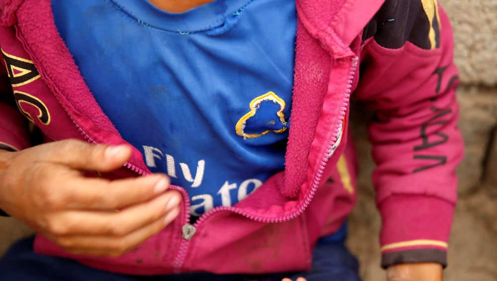 Un niño muestra su camiseta del Real Madrid con el escudo arrancado
