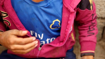 Un niño muestra su camiseta del Real Madrid con el escudo arrancado