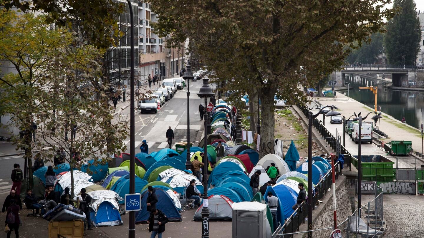 Varios inmigrantes junto a sus tiendas de campa&ntilde;a en un campamento cerca de las estaciones en Par&iacute;s, Francia