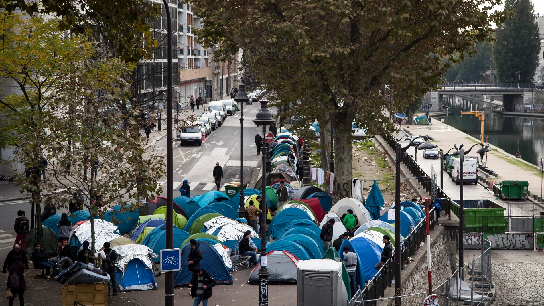 Varios inmigrantes junto a sus tiendas de campaña en un campamento cerca de las estaciones en París, Francia