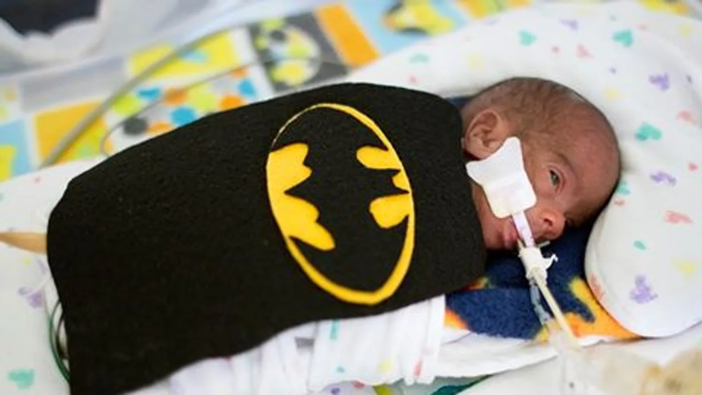 Uno de los bebés con un disfraz de Batman Uno de los bebés con un disfraz de Batman