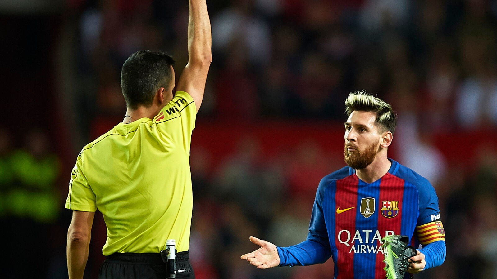 Messi ve la cartulina amarilla mientras sujeta su bota con la mano