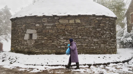 Una mujer camina bien abrigada en el alto de O Cebreiro, Lugo Una mujer camina bien abrigada en el alto de O Cebreiro, Lugo