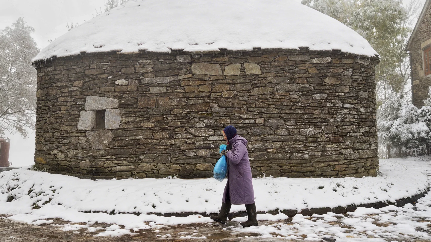 Una mujer camina bien abrigada en el alto de O Cebreiro, Lugo Una mujer camina bien abrigada en el alto de O Cebreiro, Lugo