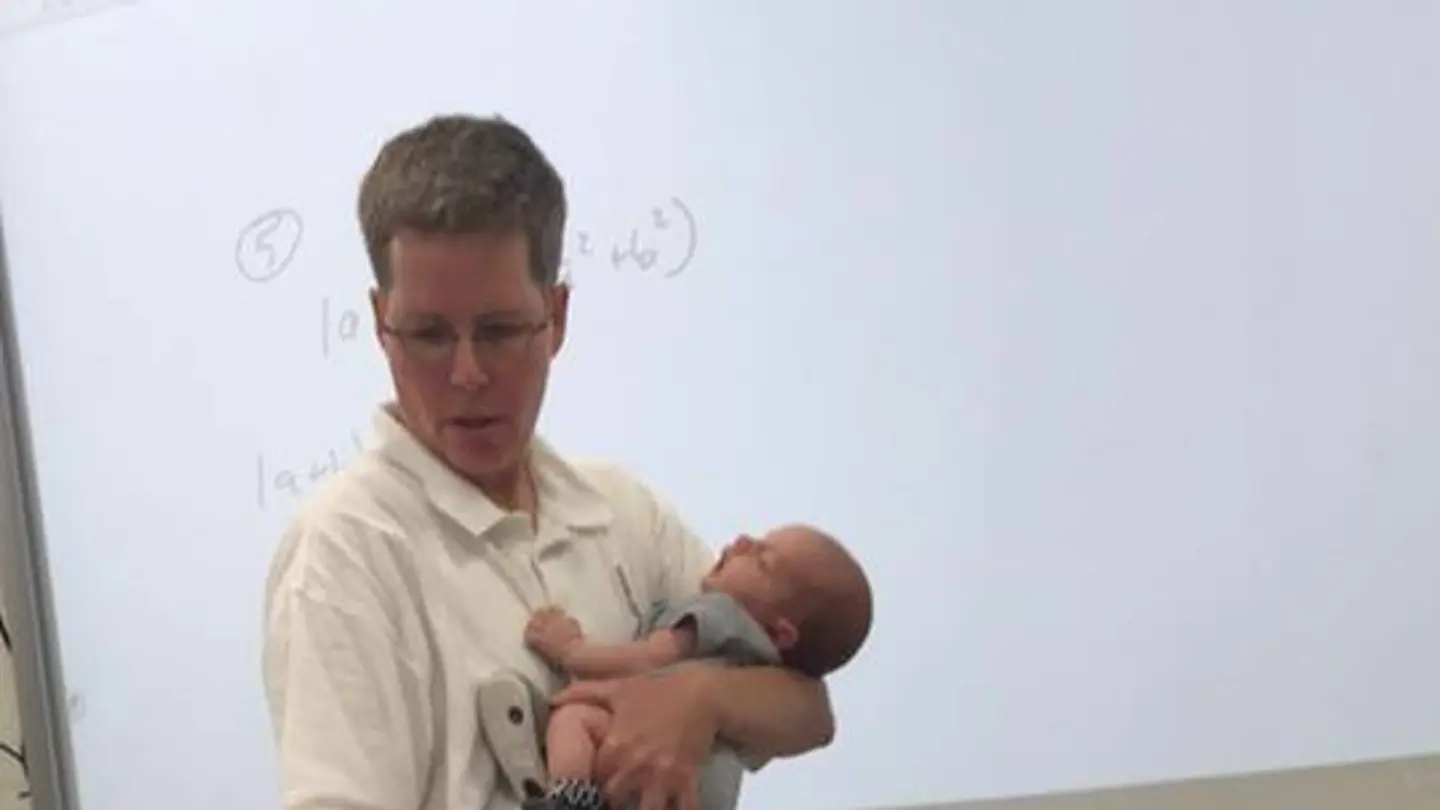 La profesora impartiendo clase con el bebé en brazos La profesora impartiendo clase con el bebé en brazos