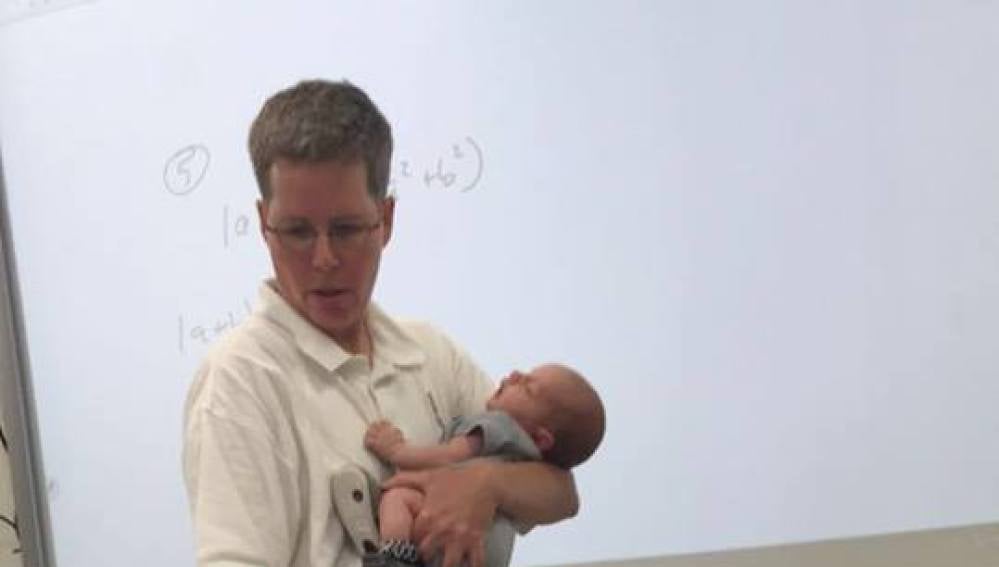 La profesora impartiendo clase con el bebé en brazos