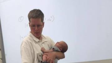 La profesora impartiendo clase con el bebé en brazos