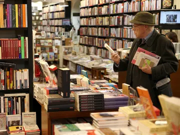 Un hombre mira un libro en una librería Un hombre mira un libro en una librería