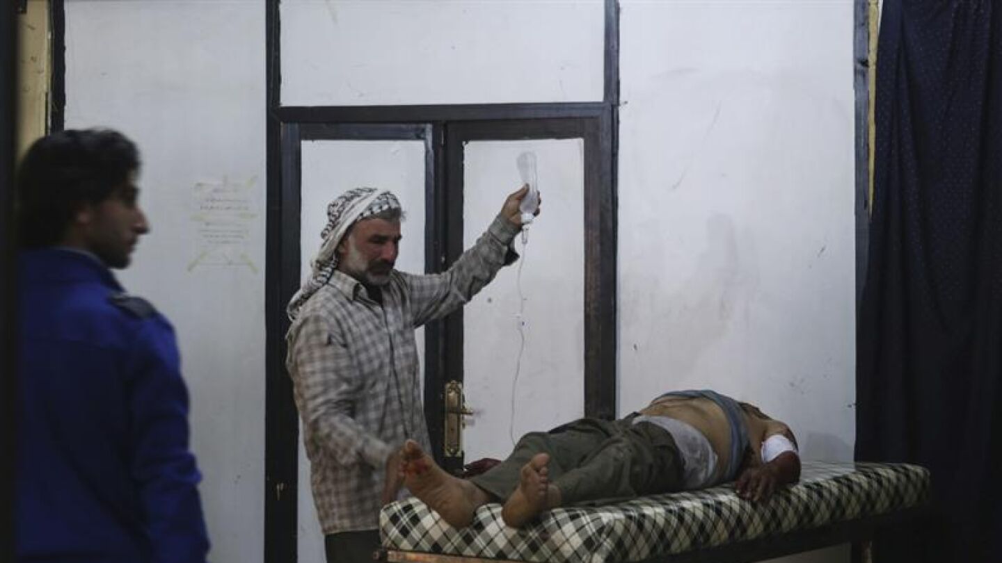 Un sirio atiende a un herido por los bombardeos en Alepo