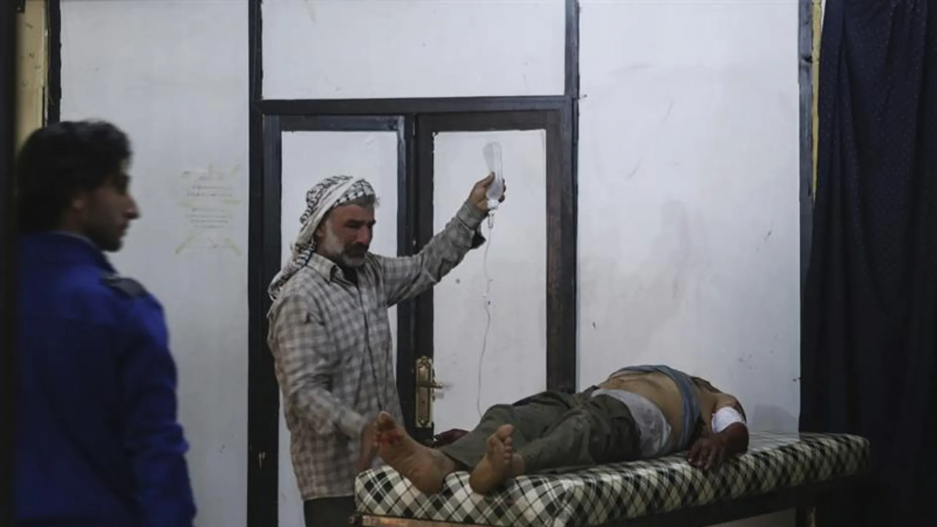 Un sirio atiende a un herido por los bombardeos en Alepo