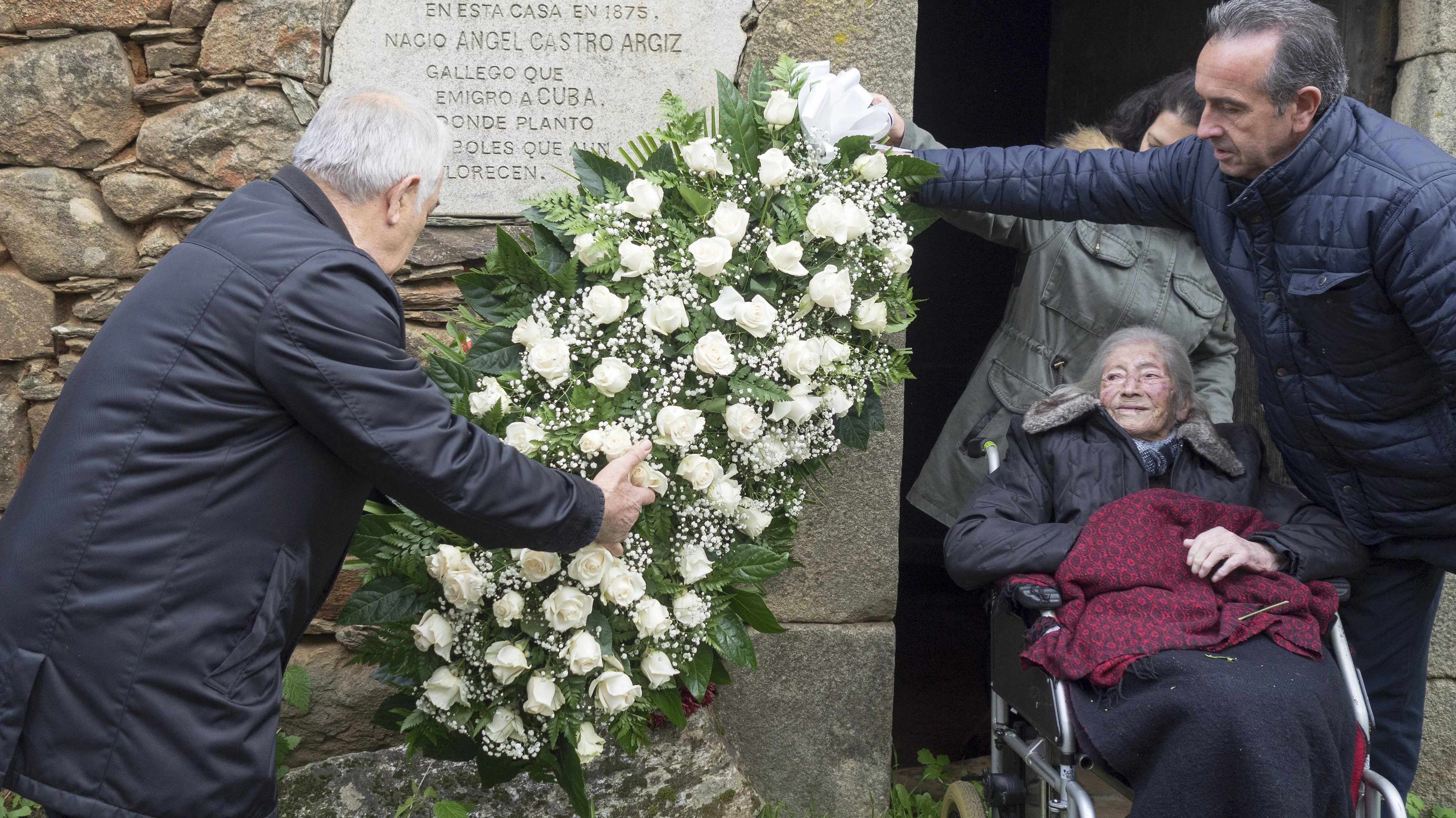 El alcalde de Láncara, Dario A. Piñeiro (d), y el anterior alcalde, Eladio Capón (i), acompañados por la prima de Fidel Castro, Manuela Argiz, de 103 años, depositan una corona de flores en la casa natal de Ángel, el padre de Fidel Castro, como homenaje al líder cubano fallecido a los 90 años en La Habana