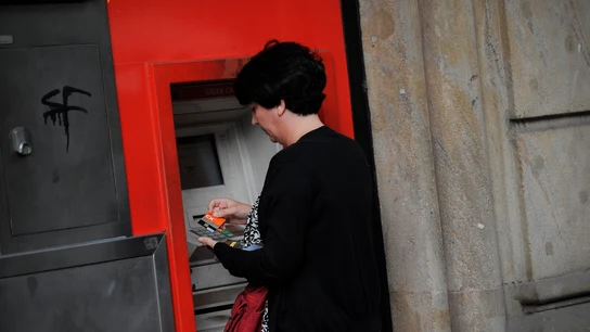 Una mujer saca dinero de un cajero automático Una mujer saca dinero de un cajero automático